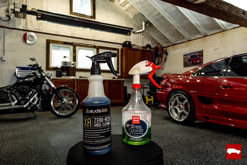 2 different bottles of wheel cleaner on a stool in a garage