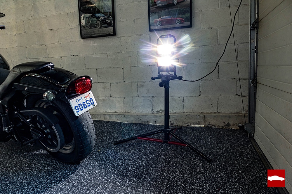 A work light on a stand beside a Harley Davidson