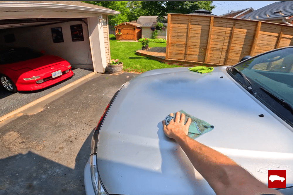 Wiping a Tacoma hood with rinseless wash on a microfiber towel
